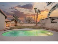 Inviting pool area with lush landscaping, palm trees, and a beautiful sunset backdrop at 7695 Silver Wells Rd, Las Vegas, NV 89149