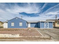 Charming single-story home with blue exterior, desert landscaping, and a driveway leading to an attached garage at 143 Constitution Ave, Henderson, NV 89015