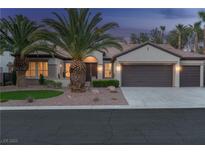 Charming single-story home with a three-car garage, desert landscaping, and mature palm trees at dusk at 1624 Preston Park Dr, Henderson, NV 89052