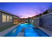 Stunning backyard pool with integrated spa and stone waterfall feature, perfect for relaxation and entertaining at 18 Via Tiberina, Henderson, NV 89011