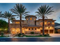 Stunning two-story stone house featuring manicured landscaping, palm trees, and a three-car garage at 2845 Red Arrow Dr, Las Vegas, NV 89135