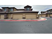 A tan condo complex featuring individual garages for each unit and tile roofing at 6868 Sky Pointe Dr # 2013, Las Vegas, NV 89131
