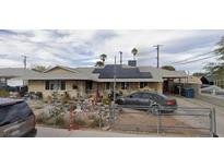 Single-story home featuring a solar panel roof, carport, and unique yard decor at 4530 Garden Pl, Las Vegas, NV 89107
