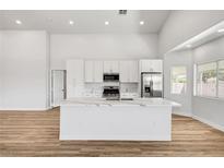 Bright kitchen features white cabinets, modern stainless appliances, and quartz countertop island at 689 Hitchen Post Dr, Henderson, NV 89011