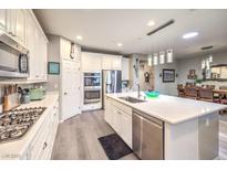 Bright kitchen features stainless steel appliances, white cabinetry, and a large kitchen island at 797 Drammatico Pl, Henderson, NV 89011