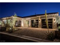 Striking home exterior featuring a stone facade and modern glass garage doors at twilight at 47 Garibaldi Way, Henderson, NV 89011