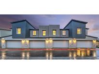 Modern townhome exterior with multiple garages and clean, contemporary design on a wet street at 6958 Lynbridge St # 62, Las Vegas, NV 89166