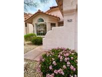 Charming home exterior with stucco walls, red tile roof, and colorful landscaping with pink flowers in the front at 7821 Desert Bell Ave, Las Vegas, NV 89128