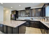 Modern kitchen boasts dark cabinetry, stainless steel appliances, granite countertops, and a large island at 12391 Pinetina St, Las Vegas, NV 89141
