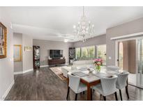 Open-concept living room featuring dark wood floors, dining table, and chandelier at 11870 Tevare Ln # 1085, Las Vegas, NV 89138