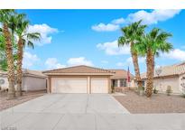 Charming single-story home featuring a three-car garage, desert landscaping, and mature palm trees at 206 Red Cloud Ter, Henderson, NV 89015