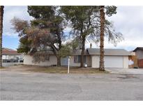 Single-story home with a beige exterior, mature trees, an attached garage, and minimal landscaping at 1847 Stevens St, Las Vegas, NV 89115