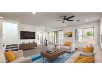 Bright living room featuring modern furniture, a ceiling fan, and sliding glass doors to the backyard at 11640 Desert Hollow Ave, Las Vegas, NV 89138