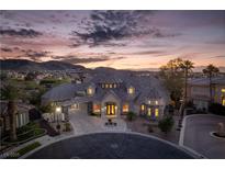 Stunning luxury home featuring stone accents, elegant architecture, and a porte cochere, set against a scenic mountain backdrop at 1800 Melfi Ct, Henderson, NV 89012