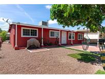 Charming single-story home featuring a red exterior, mature tree, and covered patio with a gravel yard at 2809 Webster St, North Las Vegas, NV 89030