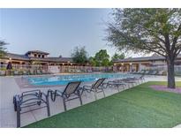 Community pool view with lounge chairs on concrete and artificial turf, surrounded by mature trees at 10422 Prairie Mountain Ave, Las Vegas, NV 89166