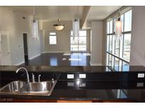 Modern kitchen featuring granite countertops, stainless steel sink, and a view of the living area with large windows at 150 N Las Vegas Blvd # 1217, Las Vegas, NV 89101