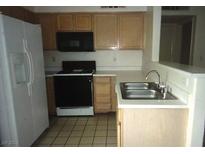 The kitchen has tile floors, black appliances and oak colored cabinets at 3041 Casey Dr # 101, Las Vegas, NV 89120