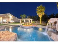Custom pool with rock waterfall, spa, and swim up bar, all illuminated at twilight at 382 Chaplin Cove Ave, Las Vegas, NV 89183