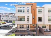 Modern three-story home with a balcony, desert landscaping, and a mix of white and tan exterior finishes at 647 Spotted Falcon St, Las Vegas, NV 89138