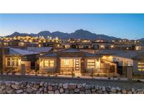 Inviting single-story home with stone accents, manicured landscaping, and mountain views at twilight at 916 Belleforte Ln, Las Vegas, NV 89138