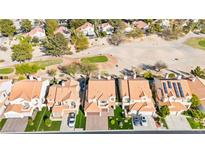 Aerial view of a residential area showcasing houses with red-tiled roofs near a golf course and desert landscape at 5492 Royal Vista Ln, Las Vegas, NV 89149