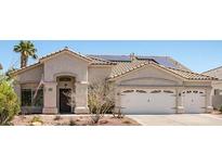 Charming single-story home featuring a two-car garage, desert landscaping, and solar panels on a tile roof at 90 Ancient Hills Ln, Henderson, NV 89074