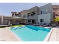 Backyard view of the sparkling pool with several lounge chairs and outdoor furniture available to enjoy the outdoor space at 302 Watteau Ct, Henderson, NV 89012
