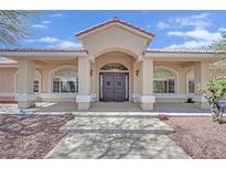 Inviting front entrance with an arched doorway and manicured landscaping at 8945 S Tenaya Way, Las Vegas, NV 89113