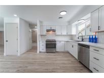 Bright white kitchen featuring stainless steel appliances, light wood floors and modern backsplash at 1808 E Saint Louis Ave, Las Vegas, NV 89104