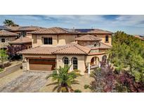 Mediterranean-style home showcasing a tile roof, arched windows, and a well-manicured front yard at 884 Loma Bonita Pl, Las Vegas, NV 89138