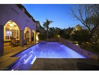 Backyard pool with blue lighting, patio with seating, and lush landscaping at 884 Loma Bonita Pl, Las Vegas, NV 89138