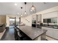 Modern kitchen features gray cabinets, a large island with seating, and stylish geometric pendant lighting at 10031 Fletcher Peak Ave, Las Vegas, NV 89178