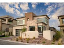 Modern two-story home boasts a neutral color palette with stone accents and a well-manicured, low-maintenance front yard at 11990 Montague St, Las Vegas, NV 89138