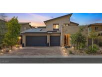 Contemporary home exterior features a three-car garage, desert landscaping and solar panels at 12356 Notch Trail Ave, Las Vegas, NV 89138