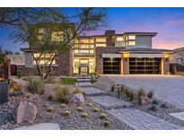 Beautiful home showcasing stone accents, a modern garage door, and landscaped front yard at 82 Glade Hollow Dr, Las Vegas, NV 89135