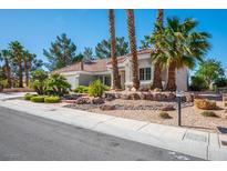Charming single-story home featuring desert landscaping with palm trees, rocks, and lush green shrubs at 9524 Quail Ridge Dr, Las Vegas, NV 89134