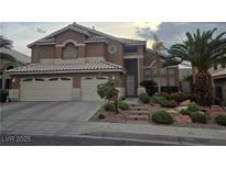 Inviting two-story home featuring a two-car garage, mature landscaping, and a charming entrance at 283 Grand Olympia Dr, Henderson, NV 89012