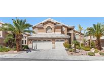 Two-story home with a two-car garage, desert landscaping, and palm trees at 283 Grand Olympia Dr, Henderson, NV 89012