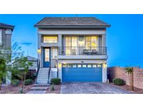 Charming two-story home featuring a blue door, balcony, blue garage door, and low-maintenance front yard at 5368 Knitmore Ct, Las Vegas, NV 89139