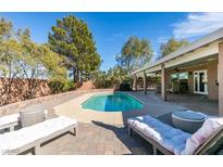 Backyard pool area showcasing a luxurious lounge area, sparkling pool water, and beautiful landscaping on a sunny day at 2246 Almart Cir, Henderson, NV 89014