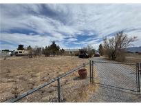 Wide exterior shot of the home with a long driveway, desert landscaping, and a chainlink fence at 3451 Ramona Ln, Pahrump, NV 89048