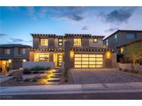 Elegant two-story home featuring a modern garage door, desert landscaping, and inviting front entrance with lit stairs at 395 Prairie Sun St, Las Vegas, NV 89138
