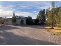 Single story home featuring desert landscaping and mature trees on a sunny day at 3491 S Bridle Way, Crystal, NV 89060