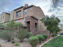 Charming multi-story townhouse featuring stone accents and desert landscaping, with an attached garage at 355 Gracious Way, Henderson, NV 89011
