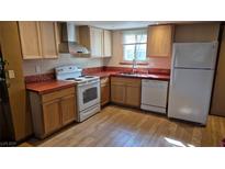 Traditional kitchen featuring light wood cabinets, white appliances, and wood-look flooring at 438 Las Casitas Way, Las Vegas, NV 89121