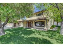 Charming two-story home with a stone facade porch, lush green lawn, and mature trees providing shade at 8970 W Lone Mountain Rd, Las Vegas, NV 89129