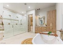 Bright bathroom featuring a glass shower, soaking tub, wood cabinets, and large walk in closet at 42 Carolina Cherry Dr, Las Vegas, NV 89141