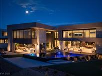 Striking modern home with infinity pool reflecting the moonlight and adjacent outdoor entertainment areas at 12 Chisel Crest Ct, Henderson, NV 89012
