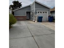 Single story home featuring an attached garage, a simple angel statue and an expansive driveway at 2302 El Molino Cir, Las Vegas, NV 89108